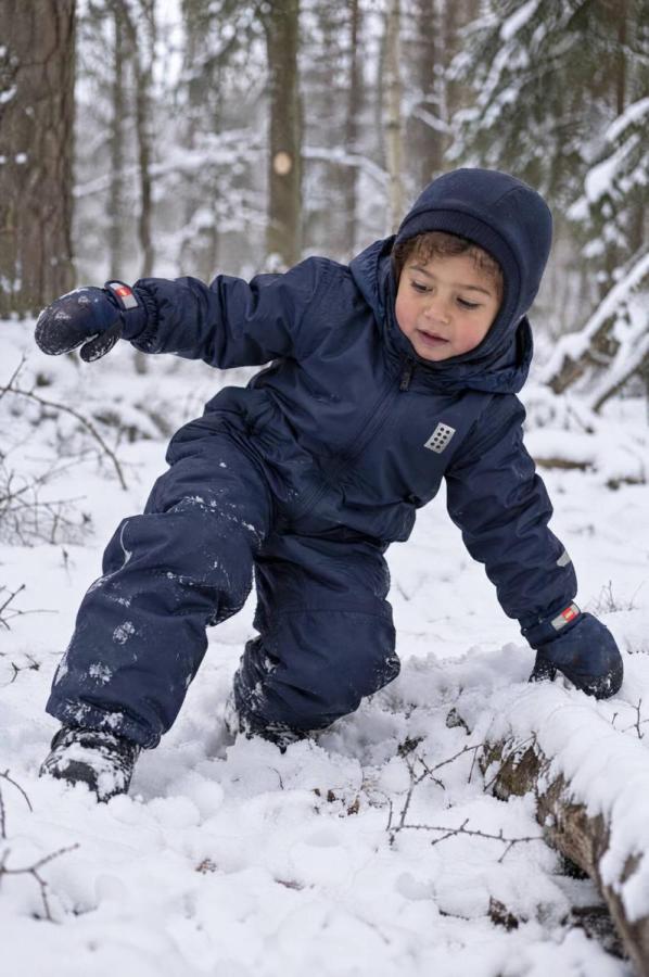 Kind im dunkelblauen Schneeanzug spielt im Schnee.
